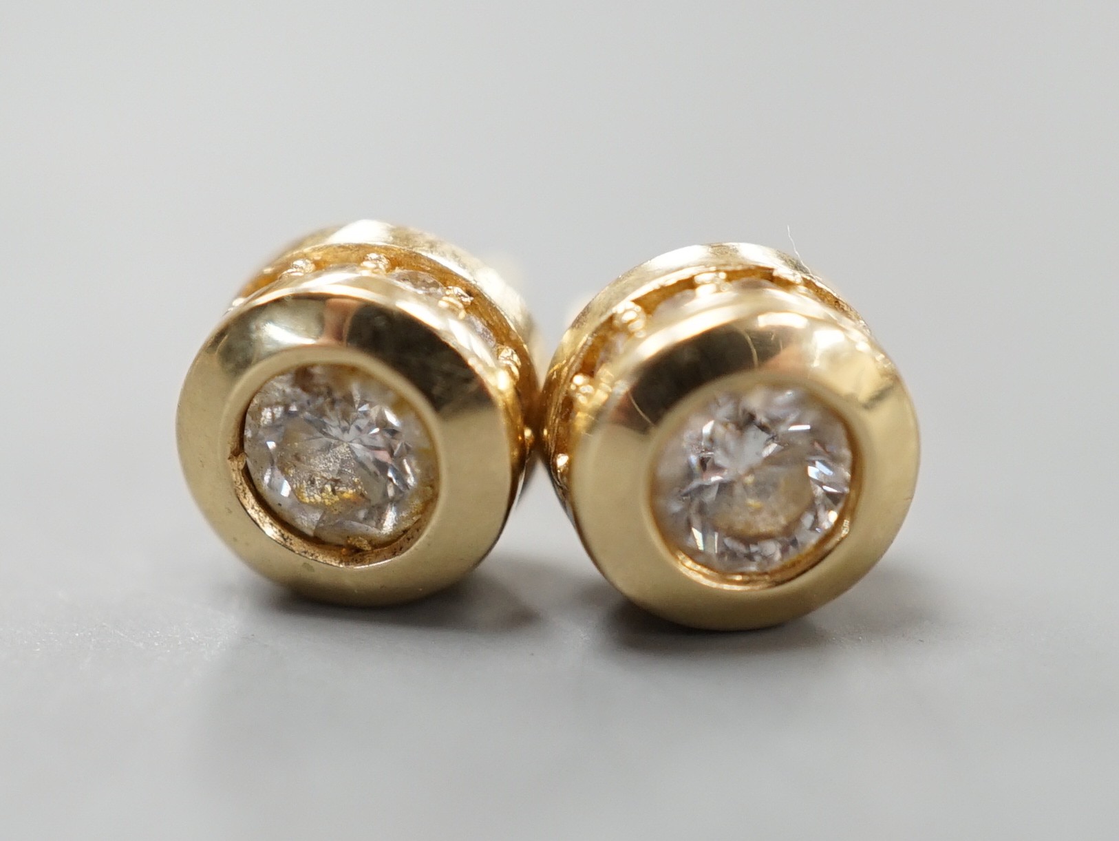 A modern pair of 14k yellow metal and single stone diamond set ear studs, with diamond chip setting, diameter 6mm, gross weight 2.8 grams.